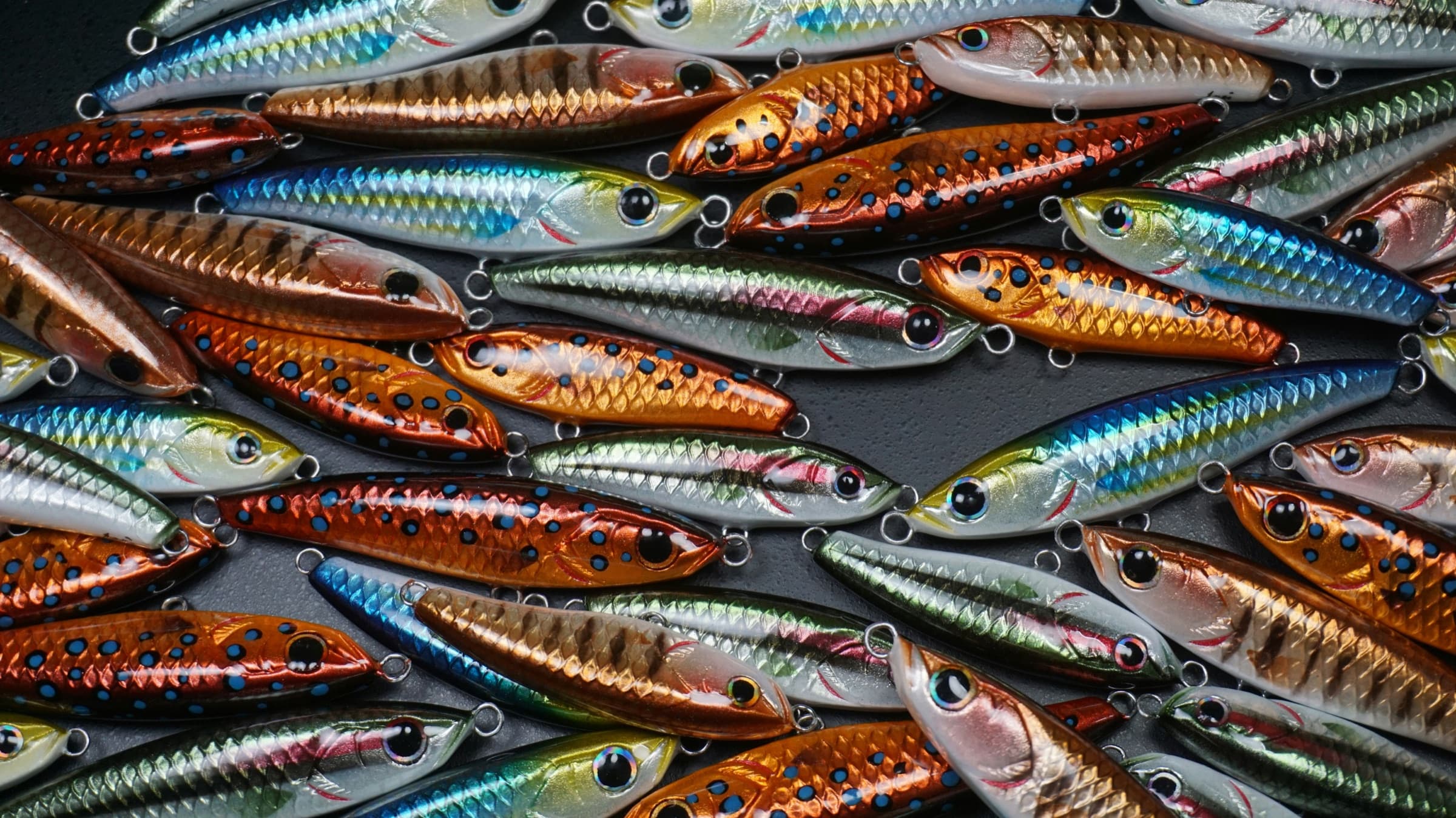 Rows of saltwater jerkbait lures in silver, blue, and orange finishes